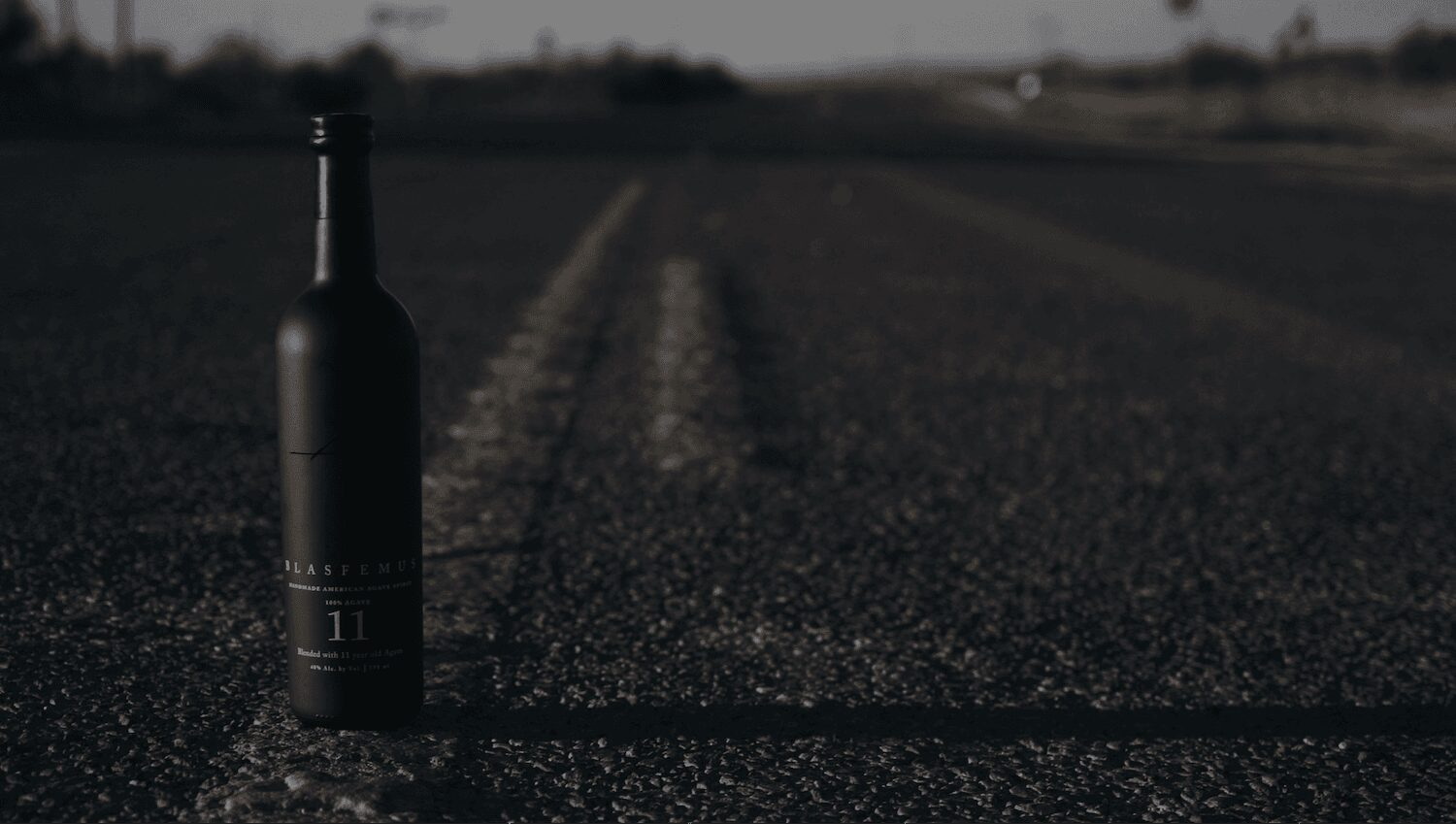 A bottle of Blasfemus in an agave field along the Rio Grande