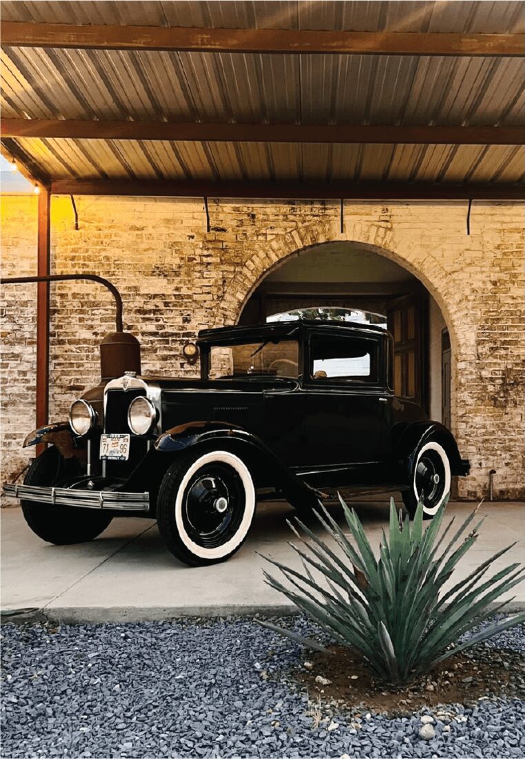 A vintage car parked under the historic brick arch at Ancestral Craft Spirits in Roma, Texas